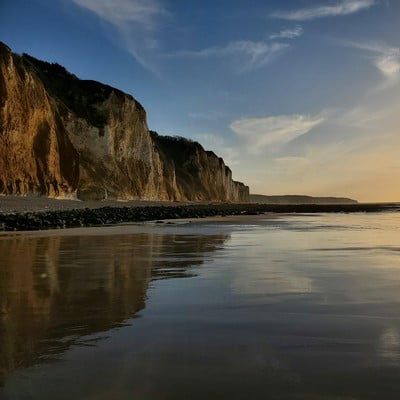 Falaises de la côte normande illuminées au coucher du soleil se reflétant sur la plage, paysage naturel exceptionnel accessible depuis la Maison Le Catelier