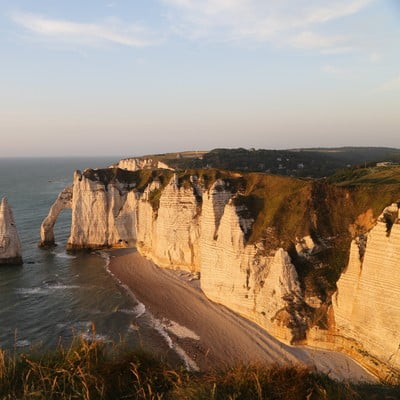 Arche naturelle et falaises d'Étretat au coucher du soleil, site touristique emblématique de Normandie à découvrir depuis la Maison Le Catelier